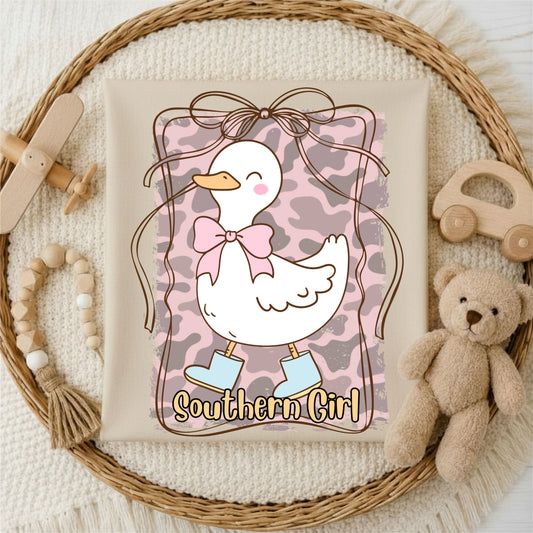 Tshirt with a duck design and 'Southern Girl' text, surrounded by toys on a textured surface.