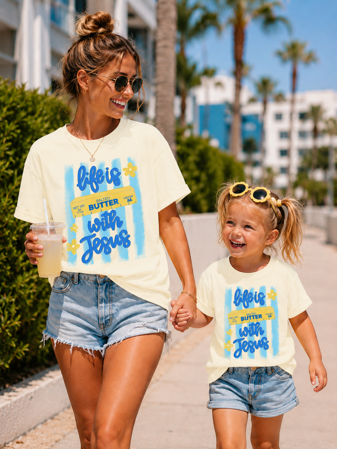 Woman and child walking together wearing matching 'Life is Butter with Jesus' t-shirts.