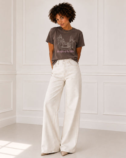 Woman wearing a Daughter of the Potter Christian graphic tee in washed Espresso Comfort Colors with ivory wide-leg jeans.