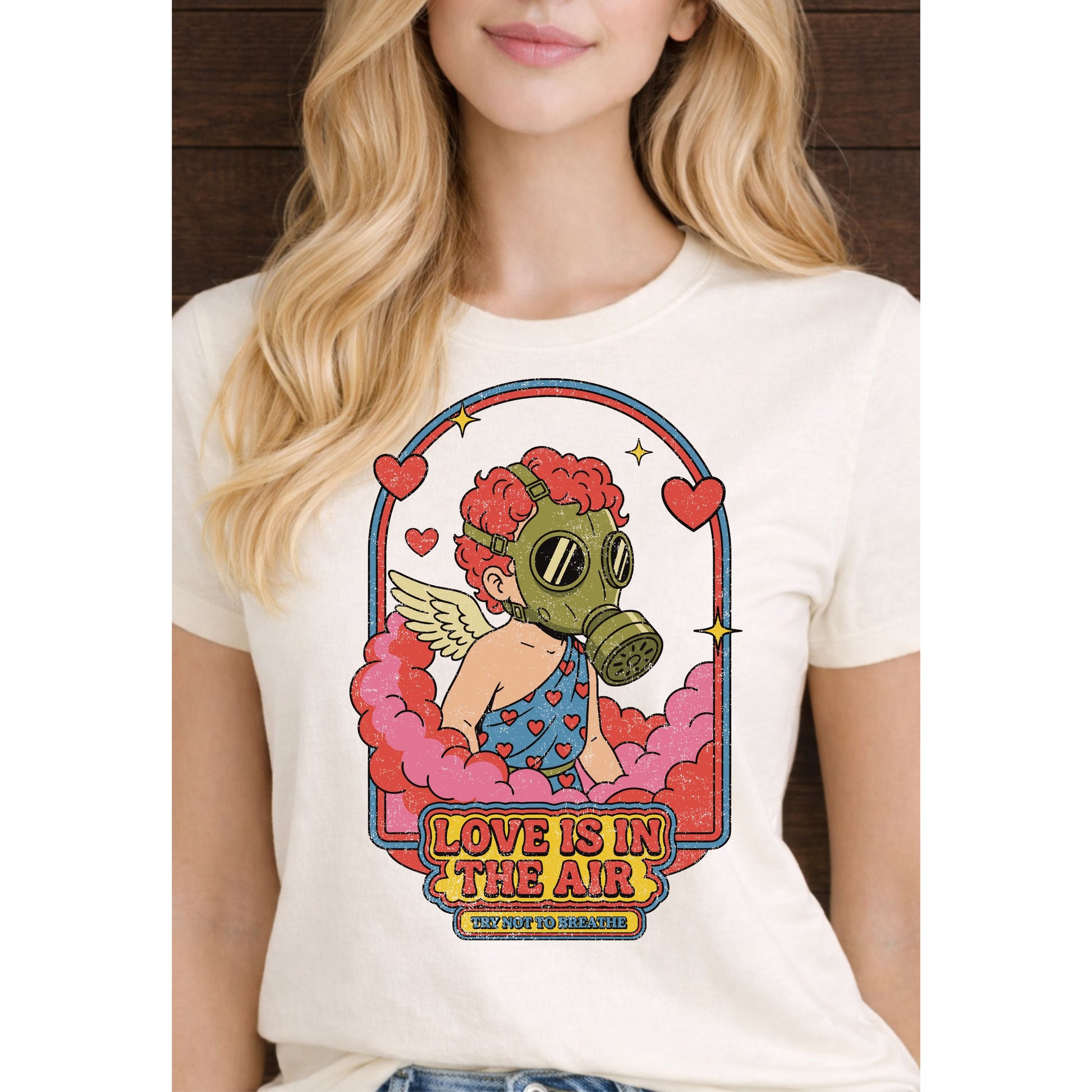 Person wearing a white t-shirt with a colorful graphic design featuring a gas mask and text 'Love is in the Air'.