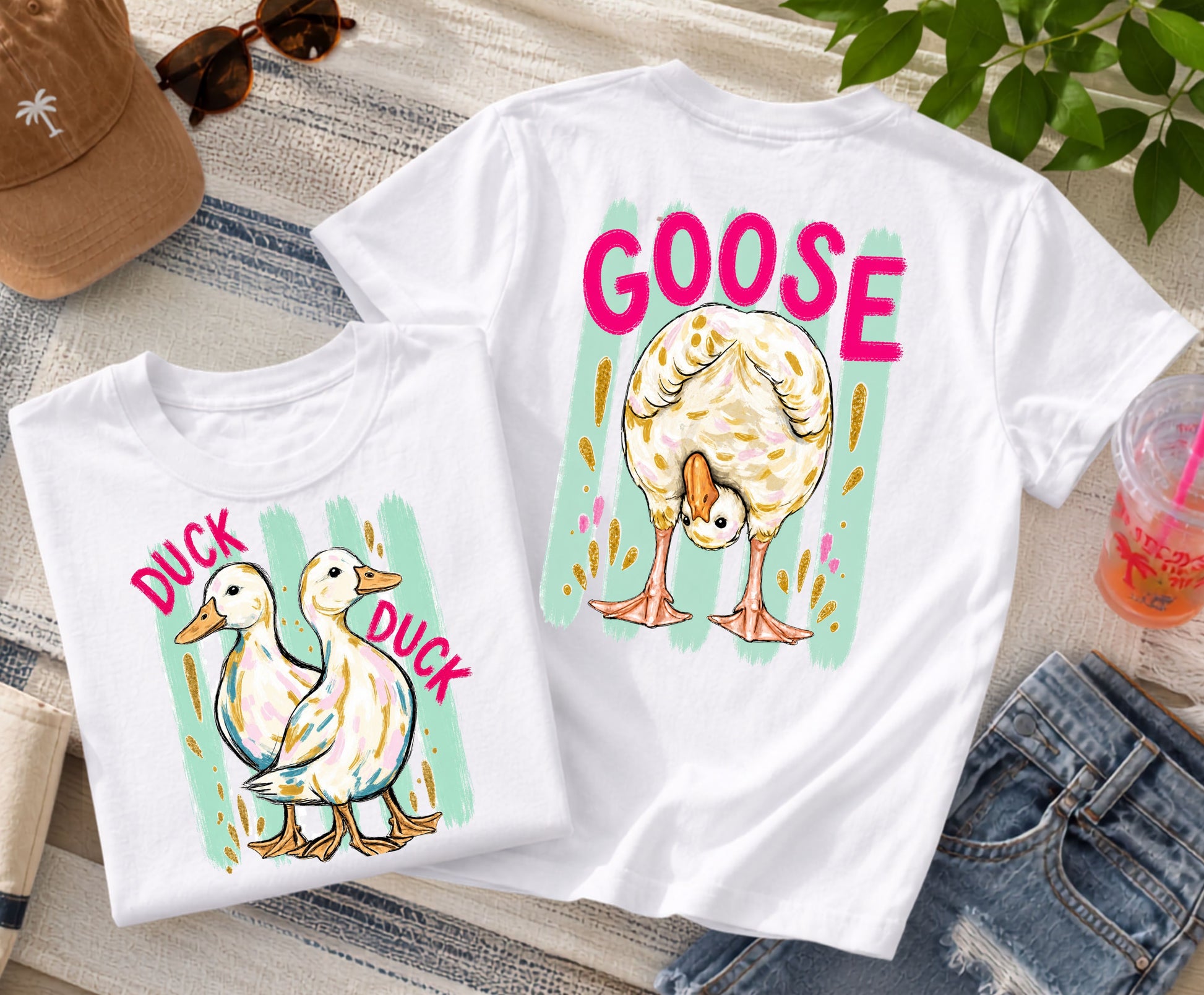 Front-and-back white graphic T-shirt featuring two ducks with the words "Duck Duck" on the front and a goose with the word "Goose" on the back, styled with denim shorts, sunglasses, a beach hat, and a colorful summer drink.