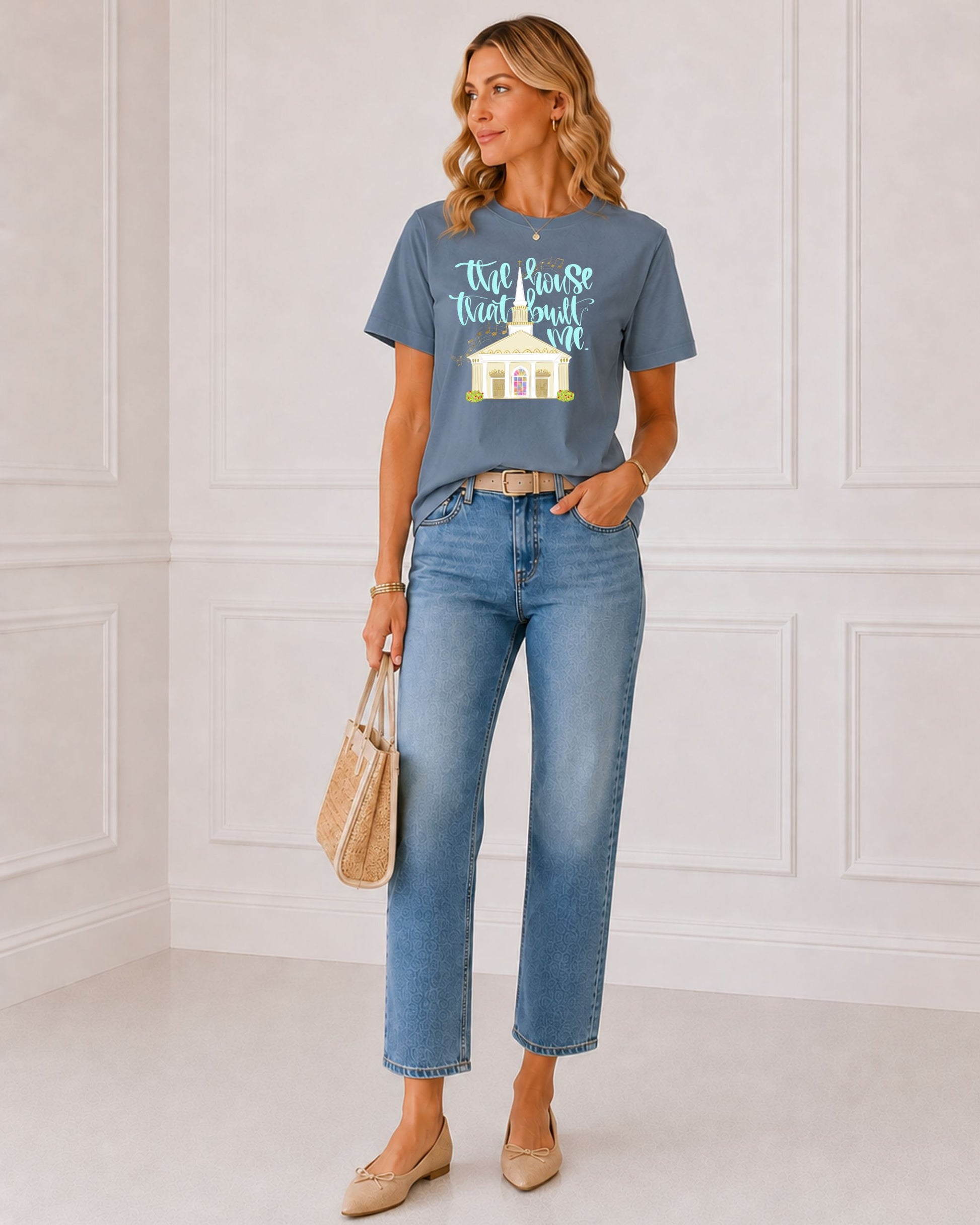 Woman modeling The House That Built Me Christian graphic tee in Washed Denim, styled with jeans, neutral flats, and a woven handbag.