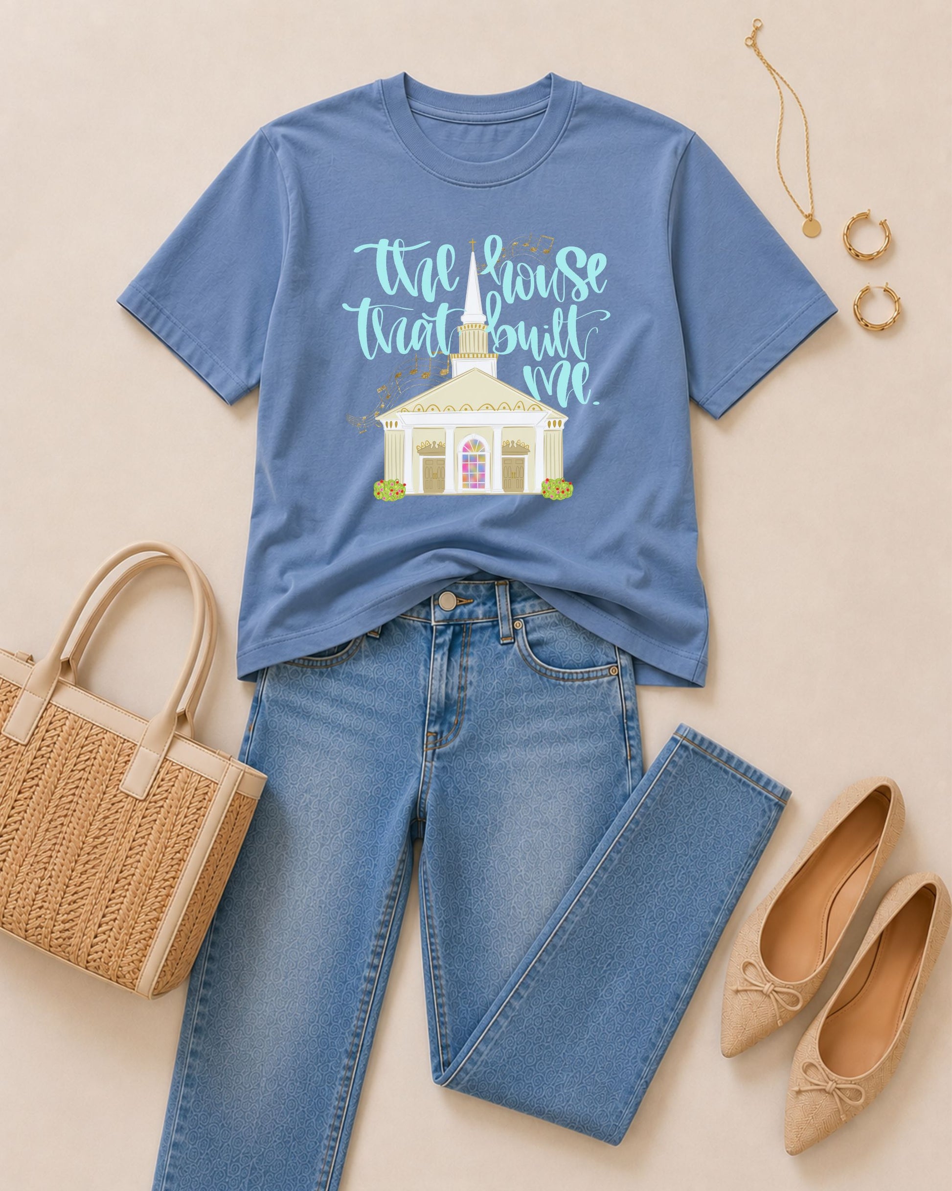 Washed Denim blue Comfort Colors T-shirt featuring The House That Built Me lettering and Southern church graphic, styled with denim jeans, neutral flats, woven tote, and gold jewelry.