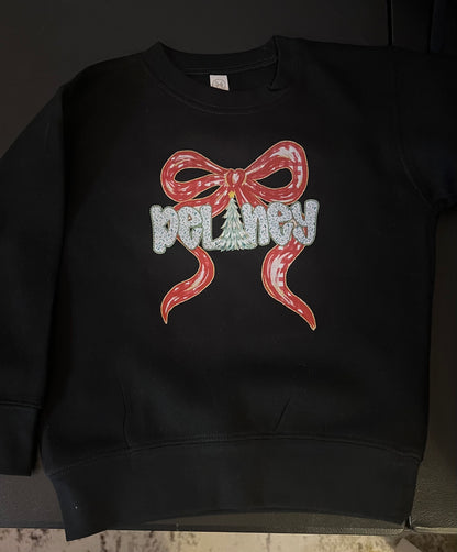 Black sweatshirt with a red bow and 'Delaney' text design on a dark background