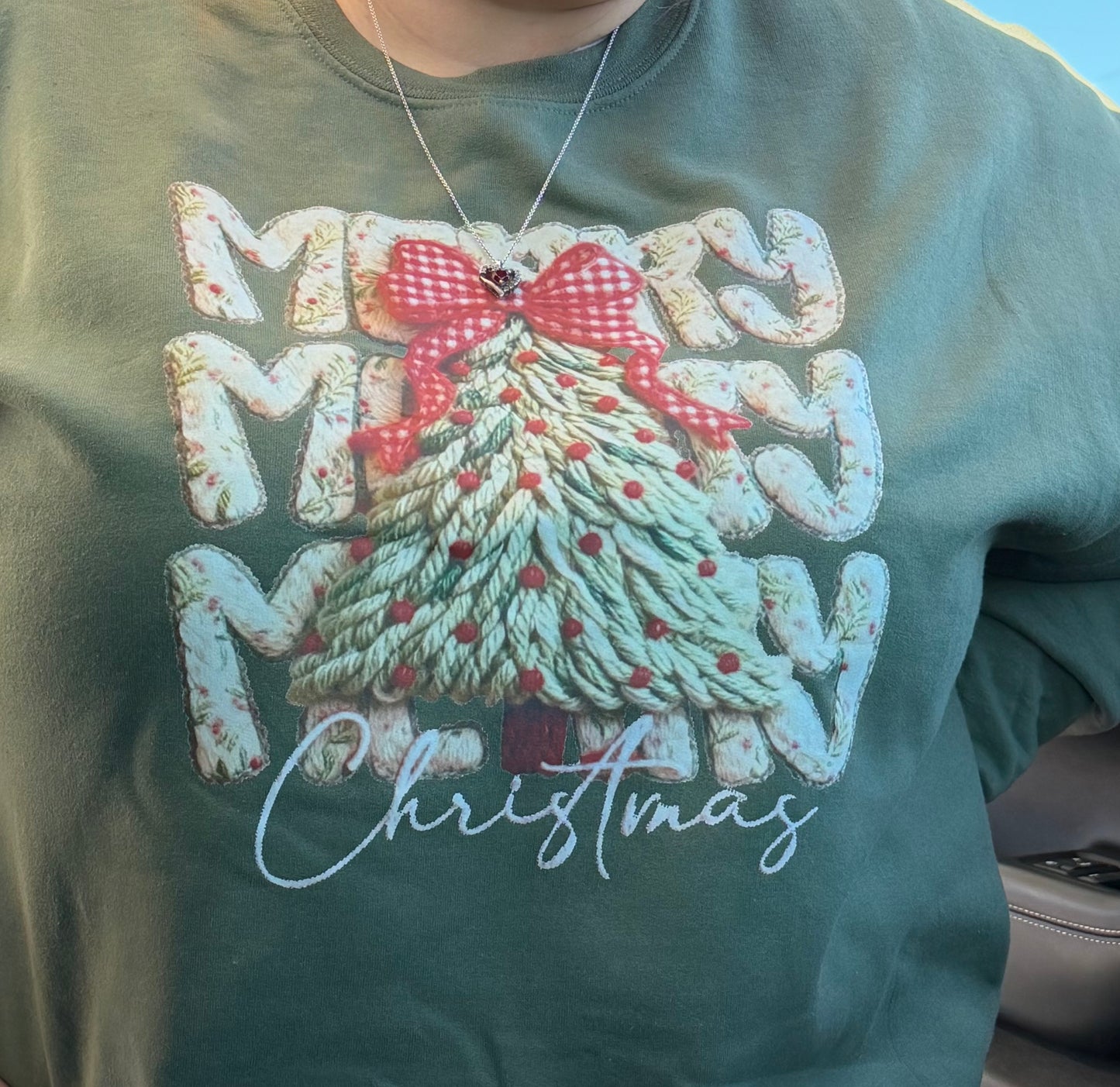 Green sweatshirt with Christmas tree and candy cane design on a light blue background