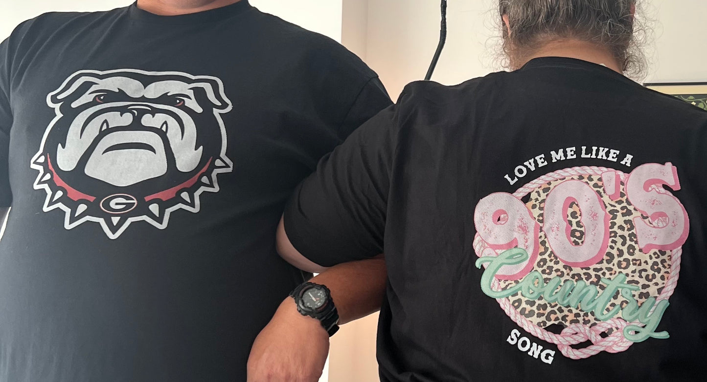 Two people wearing black t-shirts with bulldog logo and 'Love Me Like a 90s Song' design.