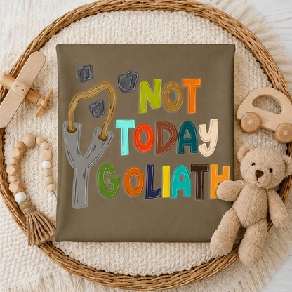 T-shirt with 'Not Today Goliath' text surrounded by toys on a textured surface