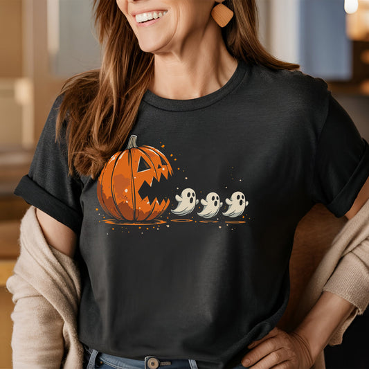 Woman wearing a gray tshirt that depicts an orange jack 'o lantern with his mouth open with three small ghosts in front of him, in the style of a popular arcade game where a yallow circle eats dots and chases ghosts to chomp for points.
