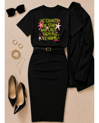 Black He Counts the Stars Psalm 147:4 Christian graphic tee styled with a black pencil skirt, blazer, heels, sunglasses, and gold jewelry.