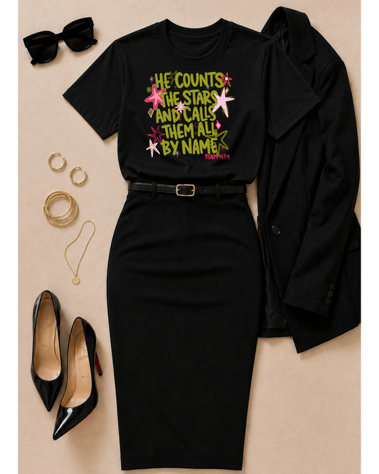 Black He Counts the Stars Psalm 147:4 Christian graphic tee styled with a black pencil skirt, blazer, heels, sunglasses, and gold jewelry.