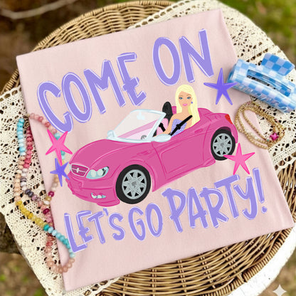 Pink t-shirt with a car graphic and text 'COME ON LET'S GO PARTY!' on a woven surface.