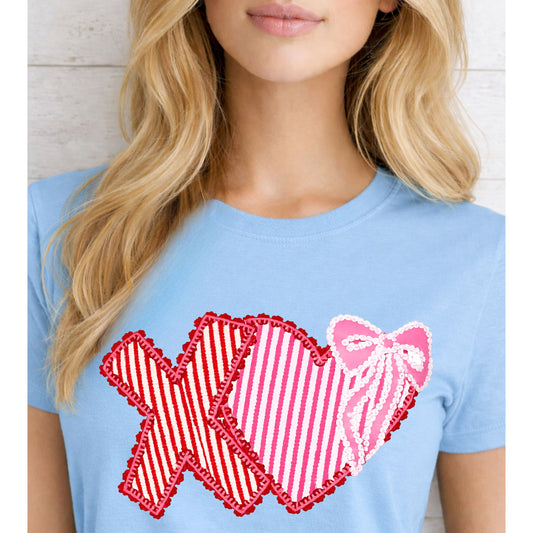Light blue t-shirt with red and pink heart designs worn by a person.
