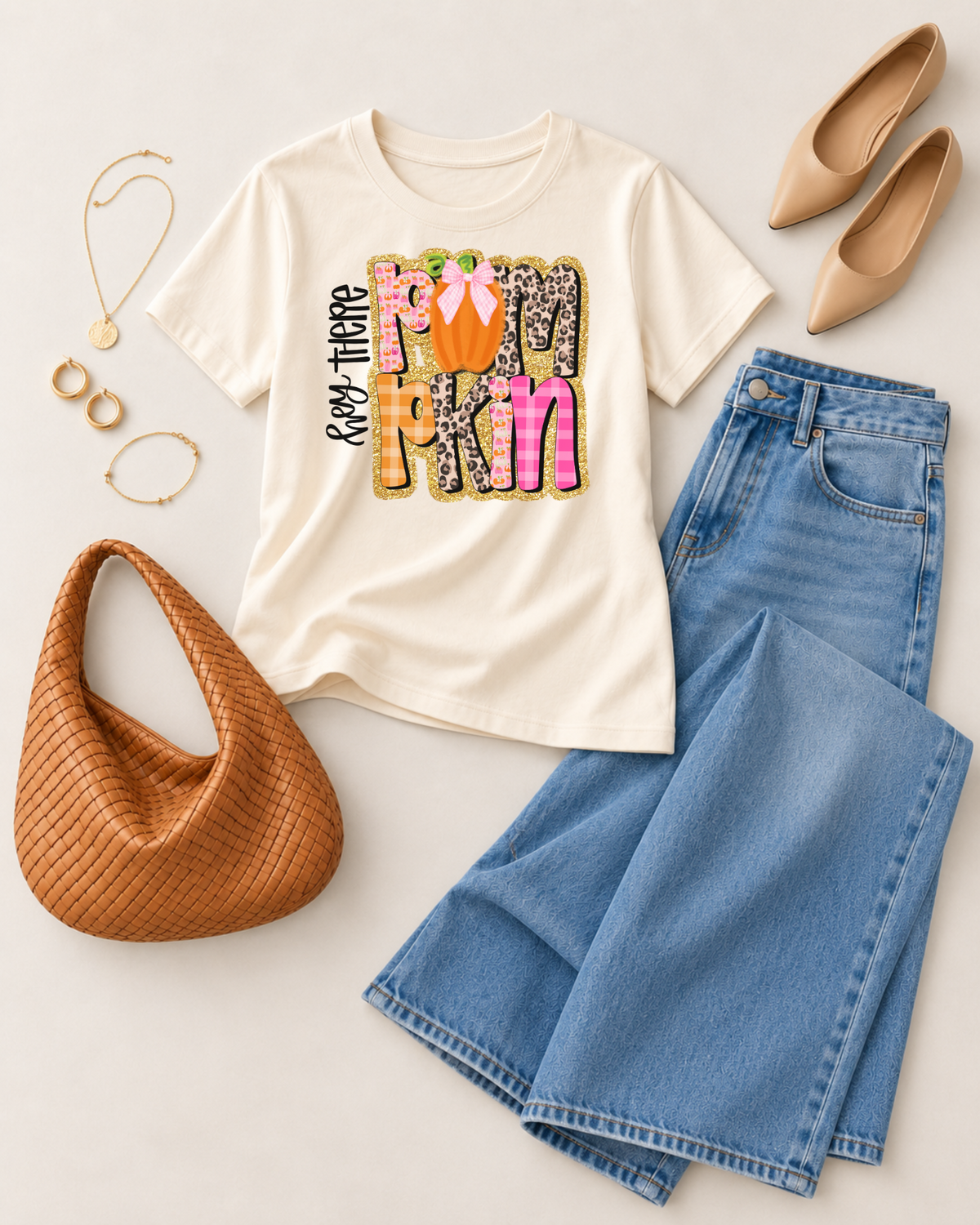 Ivory Hey There Pumpkin graphic tee styled in a flat lay with wide-leg jeans, tan flats, hobo bag, and gold jewelry